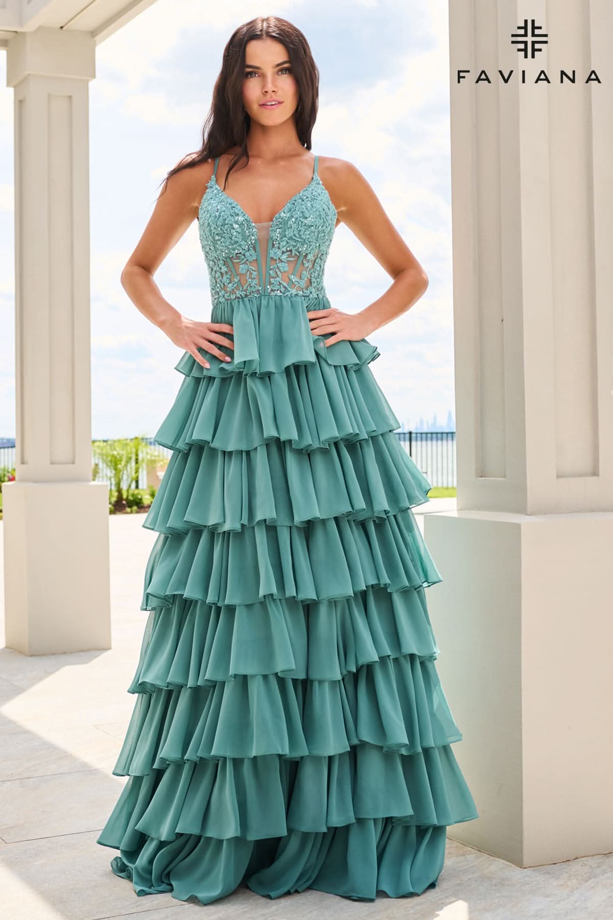 A woman modeling a teal green tiered maxi dress with a lace bodice, standing in front of a white columned building. The brand name 'FAVIANA' is visible in the top right corner.